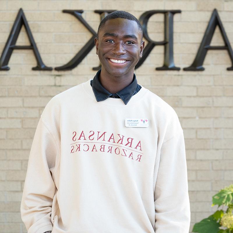 Markese Mullins stands in front of the University of Arkansas entrance sign